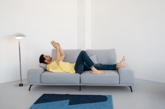 Kostenloses Foto voller schuss mann liest auf der couch