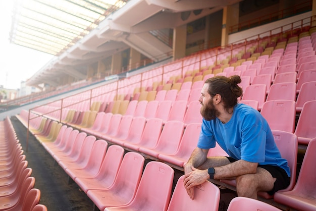 Kostenloses Foto voller schuss mann sitzt auf tribünen