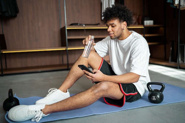 Voller Schuss Mann sitzt auf Yogamatte