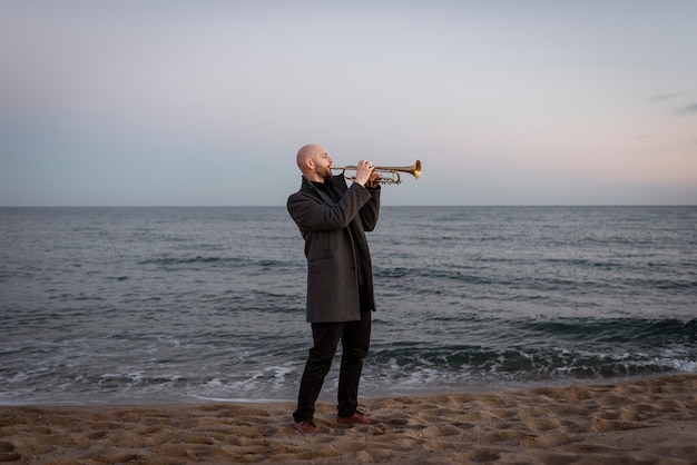 Voller Schuss Mann spielt Trompete am Meer