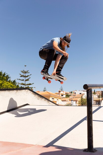 Voller Schuss Mann springt hoch mit Skateboard