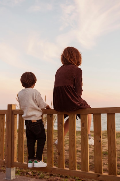 Kostenloses Foto voller schuss niedliche kinder, die auf zaun sitzen