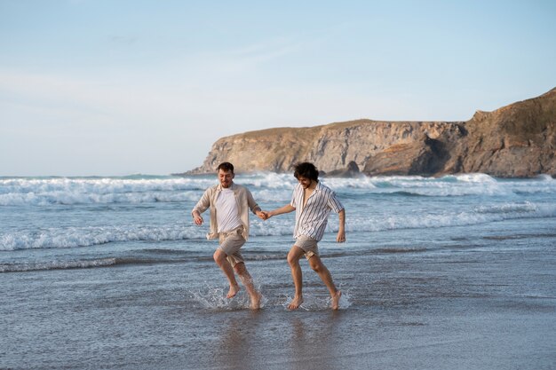 Voller Schuss schwule Männer, die am Strand Händchen halten