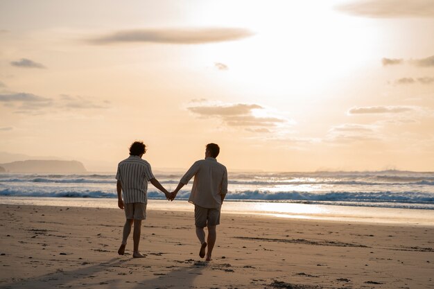 Voller Schuss schwule Männer, die am Strand Händchen halten