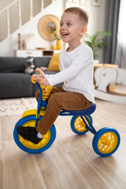 Voller Schuss Smiley-Kind, das zu Hause Dreirad fährt