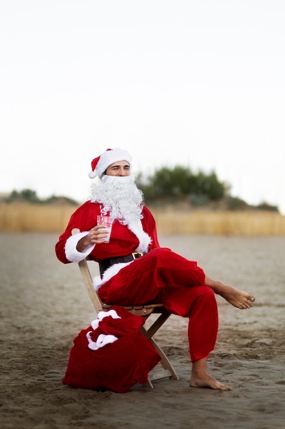 Voller schuss weihnachtsmann, der auf stuhl sitzt