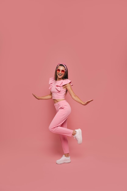 Volles Foto von einer Frau, die mit einem rosa Outfit posiert