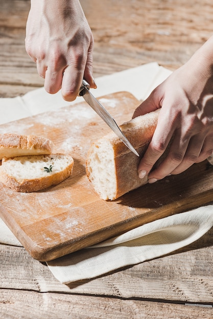 Vollkornbrot auf Küchenholzplatte mit einem Koch, der Goldmesser zum Schneiden hält.