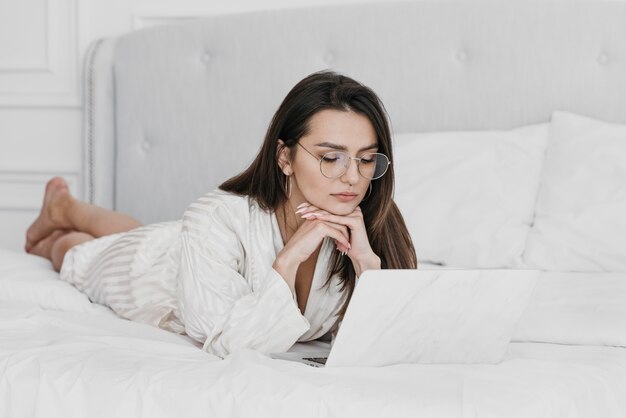 Vollschuss Frau, die im Bett mit Laptop arbeitet