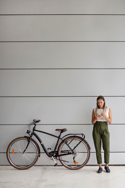 Kostenloses Foto vollschuss frau, die nahe fahrrad steht