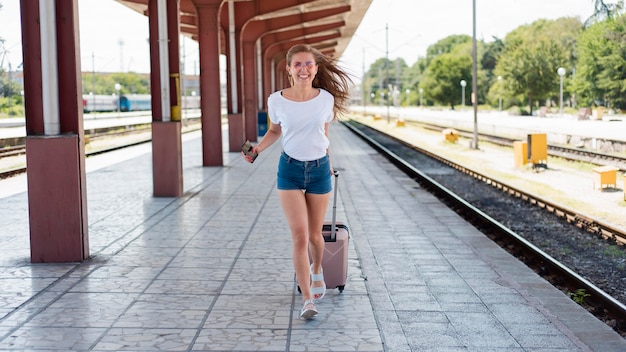 Kostenloses Foto vollschuss frau läuft mit gepäck im bahnhof