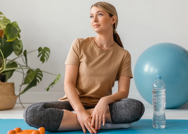 Kostenloses Foto vollschuss frau sitzt auf yogamatte