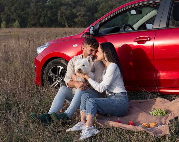 Vollschuss glückliches Paar auf Gras mit Hund