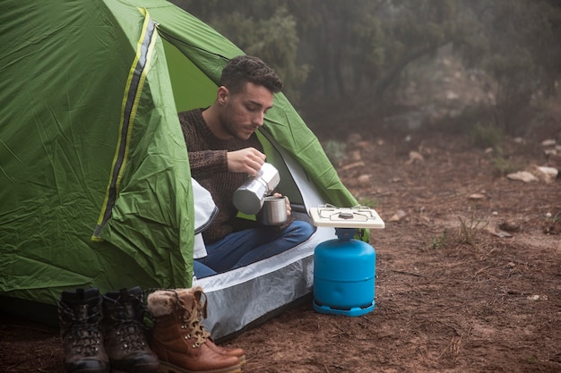 Kostenloses Foto vollschuss mann im zelt mit becher