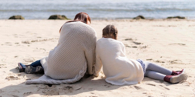 Vollschuss Mutter und Kind sitzen auf Sand