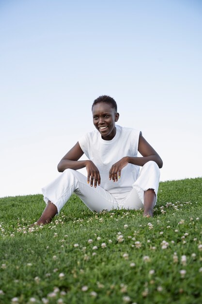 Vollschuss-Smiley-Frau, die auf Gras sitzt