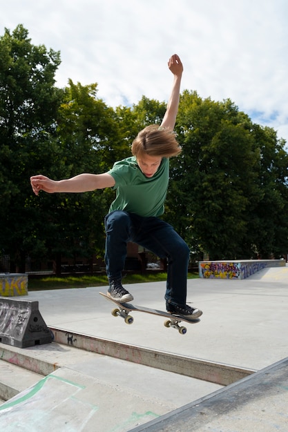 Kostenloses Foto vollschussjunge, der trick auf skateboard tut