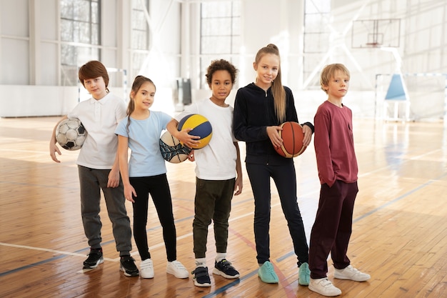 Kostenloses Foto vollschusskinder, die bälle im fitnessstudio halten