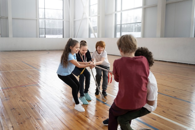 Vollschusskinder, die im Fitnessstudio Seil ziehen