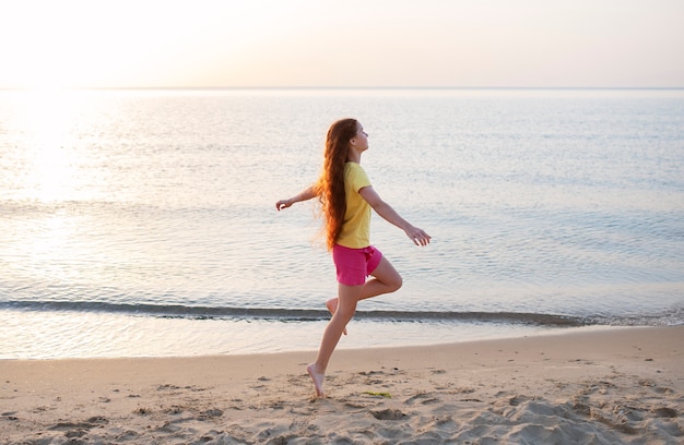 Kostenloses Foto vollschussmädchen, das am strand läuft