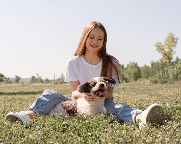 Vollschussmädchen, das auf Gras mit Hund sitzt