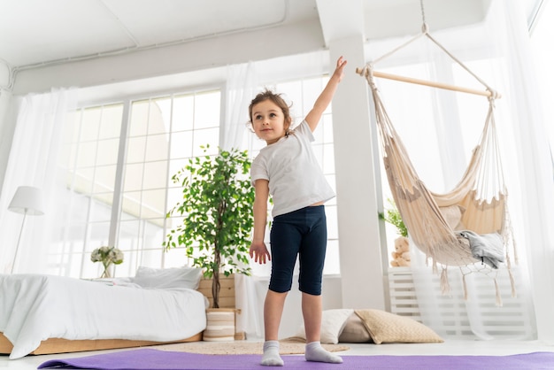 Vollschussmädchen, das auf Yogamatte steht