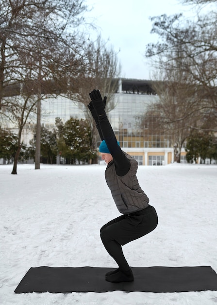 Kostenloses Foto vollschussmann, der bei kaltem wetter yoga macht