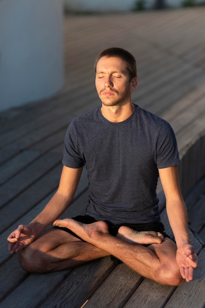 Vollschussmann, der Sukhasana-Pose im Freien auf Dock tut