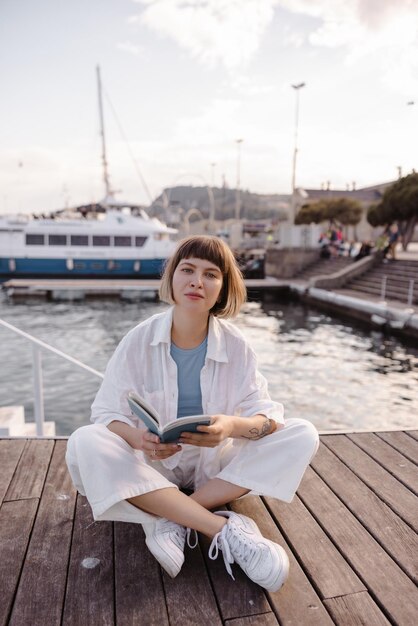 Vollständige Ansicht der Frau, die auf dem Hintergrund von Yachten sitzt