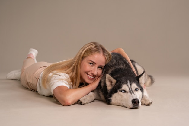 Kostenloses Foto vollständige aufnahme einer frau mit hund im studio