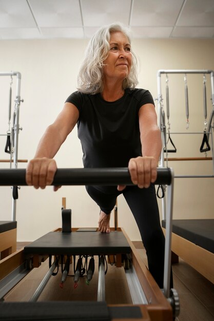 Vollständige Senior-Frau im Pilates-Reformer-Kurs