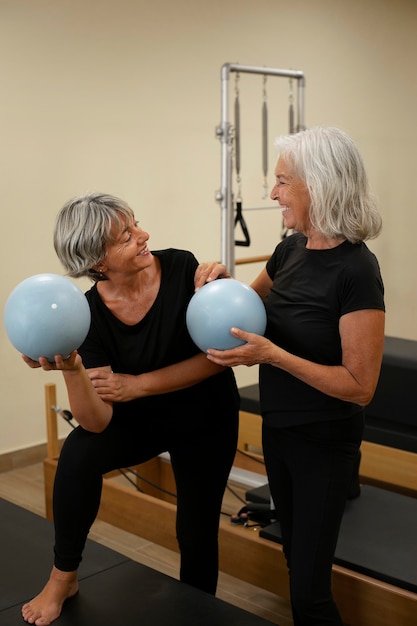 Vollständige Senior-Frauen in der Pilates-Reformer-Klasse