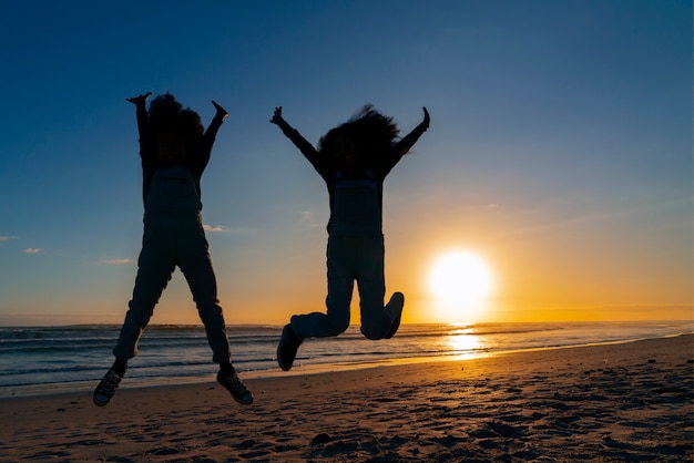 Vollständige Silhouetten von Menschen, die bei Sonnenuntergang springen