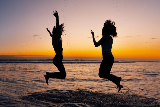 Vollständige Silhouetten von Menschen, die bei Sonnenuntergang springen