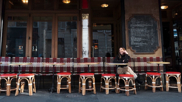 Kostenloses Foto vollständige smiley-frau, die im bistro sitzt