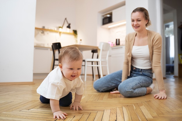 Vollständige Smiley-Mutter, die das Krabbeln des Babys beobachtet