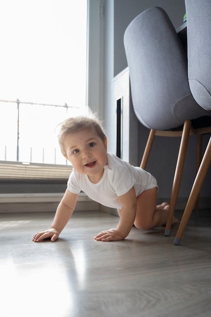 Kostenloses Foto vollständiges smiley-baby, das auf dem boden kriecht