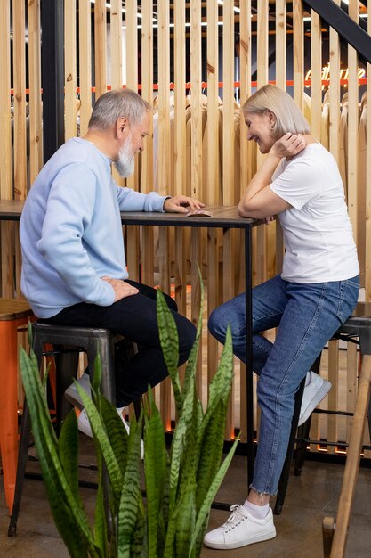 Vollständiges Smiley-Paar, das am Tisch sitzt