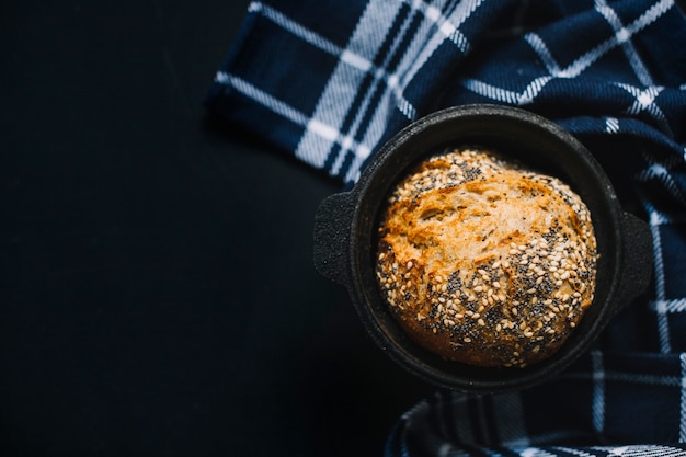 Vollweizenbrot mit Samen im schwarzen Behälter auf schwarzem Hintergrund