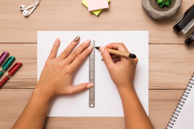 Von den oben genannten weiblichen Händen, die auf Papierblatt mit Stift und Machthaber zeichnen