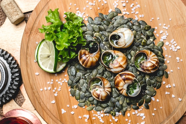 Kostenloses Foto von oben gefüllte schnecken auf kürbiskernen mit limettenscheiben