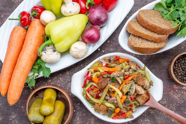 Von oben gesehen köstlicher Fleischsalat mit geschnittenem Fleisch und gekochtem Gemüse zusammen mit eingelegtem Brotgrün auf braunem Speisenfleisch