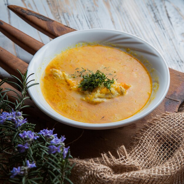 Von oben Hühnersuppe mit Rosmarinblättern und Gemüse im Food Board