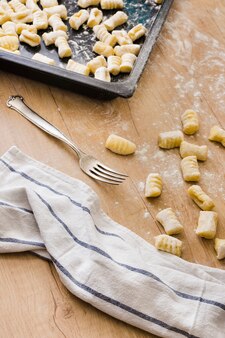 Vorbereitung von frischen italienischen teigwaren gnocchi mit gabel und serviette auf holztisch