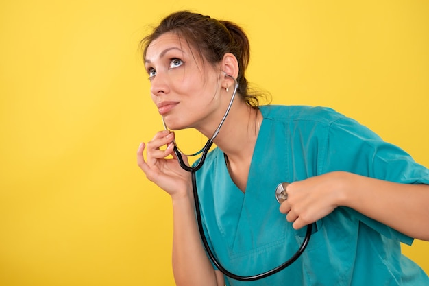 Vorderansicht ärztin im medizinischen hemd mit stethoskop auf gelbem hintergrund
