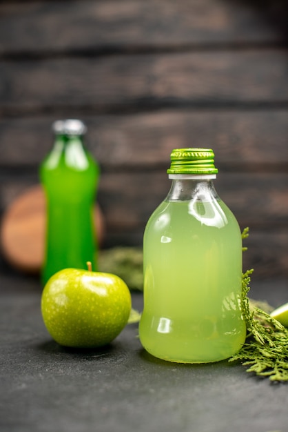 Kostenloses Foto vorderansicht apfelsaft in flasche apfel geschnittene äpfel grüne flasche auf holzoberfläche
