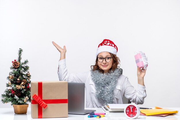 Vorderansicht Arbeiterin sitzt vor ihrem Arbeitsplatz und hält wenig Geschenk