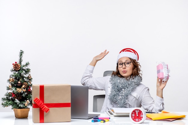 Vorderansicht Arbeiterin sitzt vor ihrem Arbeitsplatz und hält wenig Geschenk