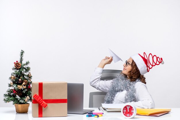 Vorderansicht Arbeiterin sitzt vor ihrem Arbeitsplatz und spielt mit Papierfliegern Arbeit Job Emotionen Business Office Weihnachten