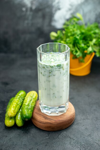 Vorderansicht-Atlama-Joghurt-Getränk mit Grün im Glas auf Holzbrettgurken auf grauem, isoliertem Tisch